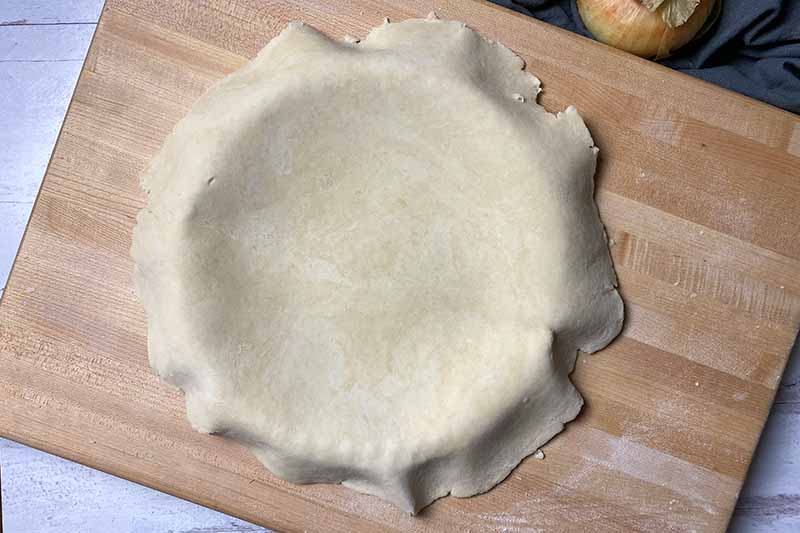 Horizontal image of a thin dough covering a pan.