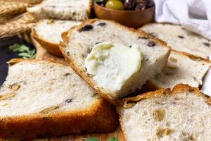 Horizontal image of slices of bread, one slathered in butter with a sprinkle of salt on top.