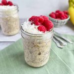 Horizontal image of jars filled with a creamy mixture topped with coconut shreds and fresh fruit on a blue napkin.
