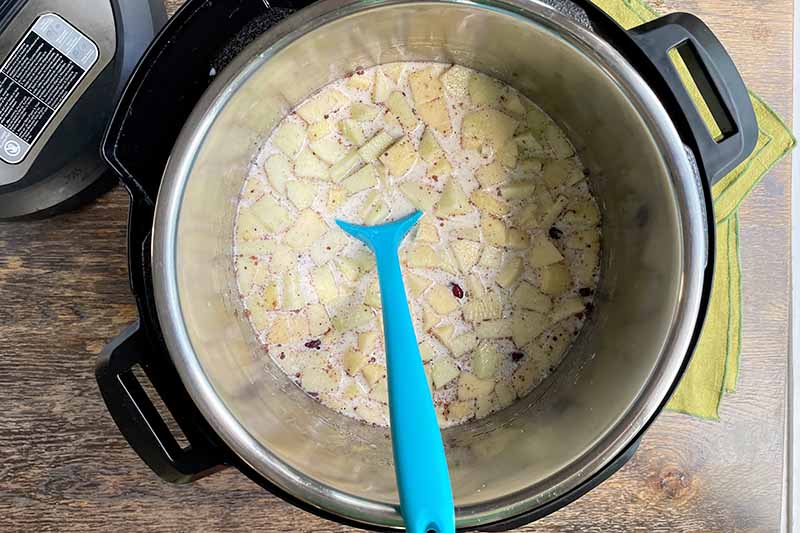 Horizontal image of mixing together ingredients in a slow cooker insert.