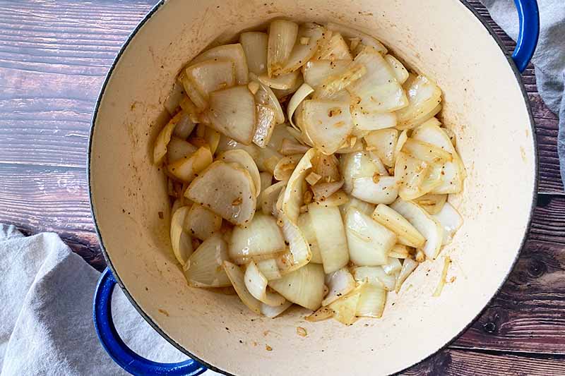 Horizontal image of caramelizing onions and garlic in a Dutch oven.