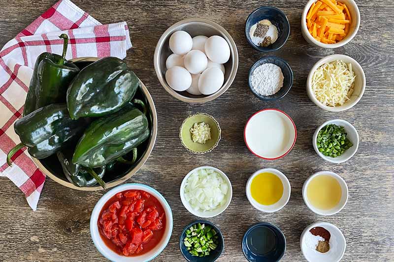 Horizontal image of assorted measured and prepped ingredients next to a bowl of fresh poblano peppers.