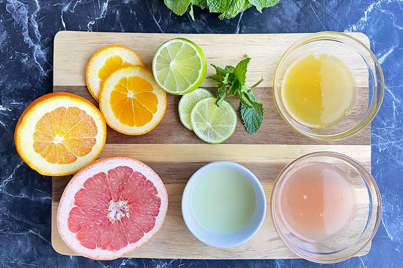 Horizontal image of various citrus juices in bowls.