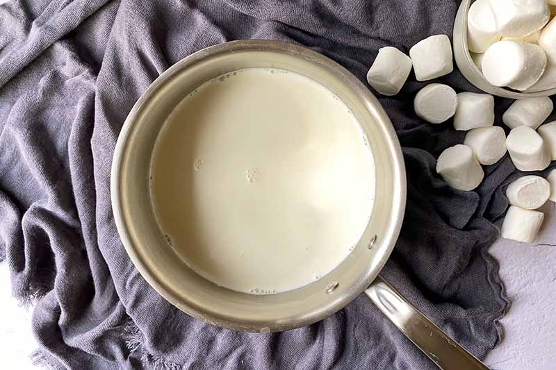 Horizontal image of heating milk in a pot.