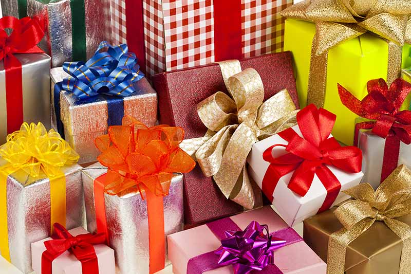 Horizontal image of assorted colorful presents with ribbons and bows.