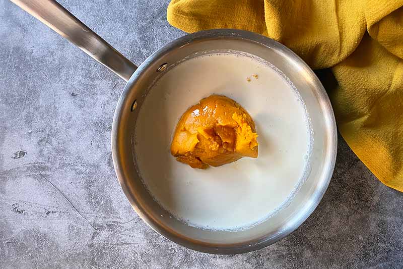 Horizontal image of pureed kabocha in milk in a pot.