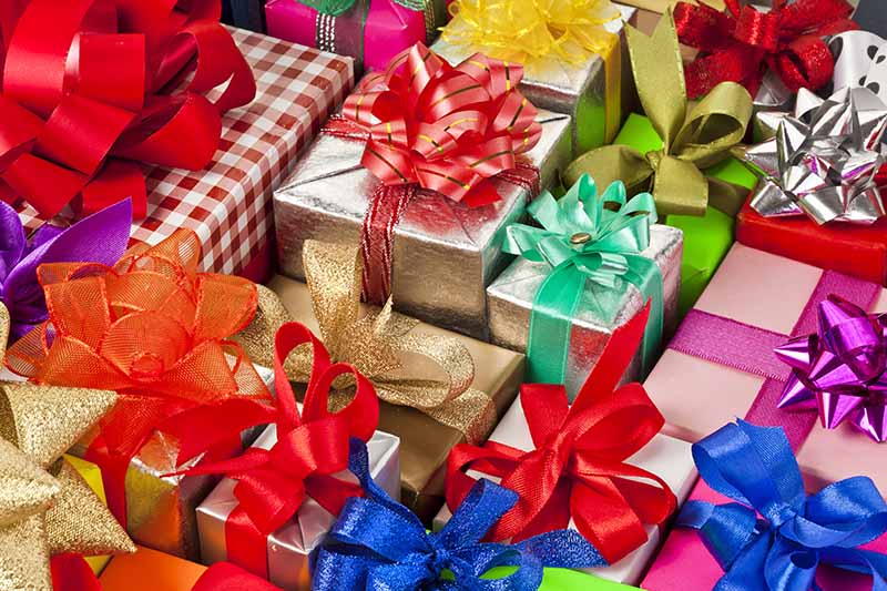Horizontal image of assorted presents wrapped with colorful wrapping papers and bows.