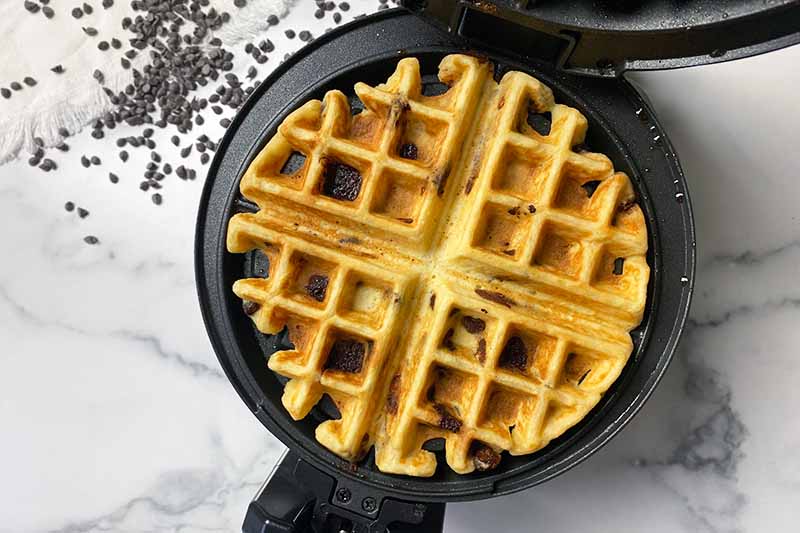 Horizontal image of a fully cooked waffle in an iron.