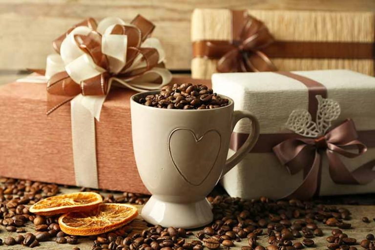 Horizontal image of presents and a mug filled with espresso beans next to dried orange slices.