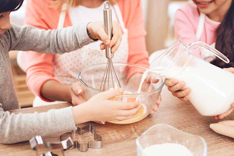 Horizontal image of children baking around the kitchen table.