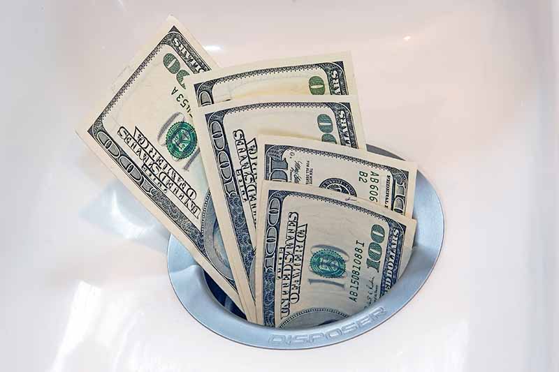 Horizontal image of money going down a drain.