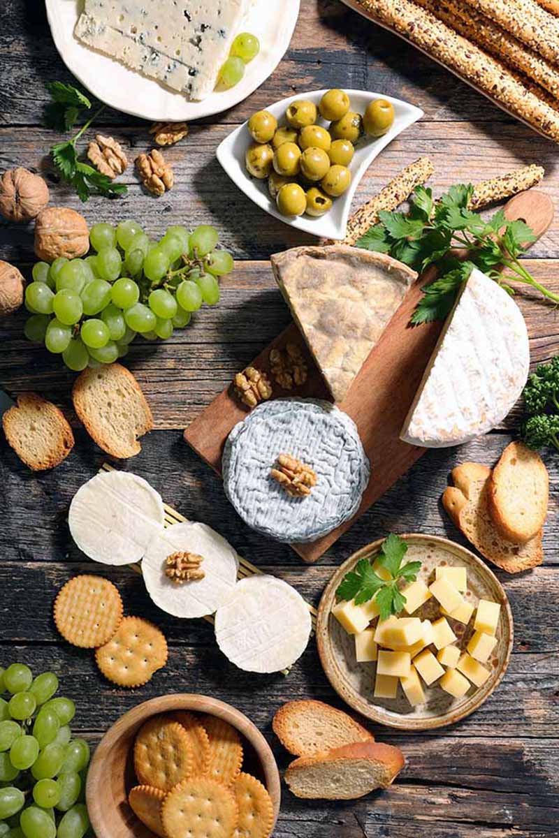 Vertical top-down image of a large appetizer spread on a wooden board.