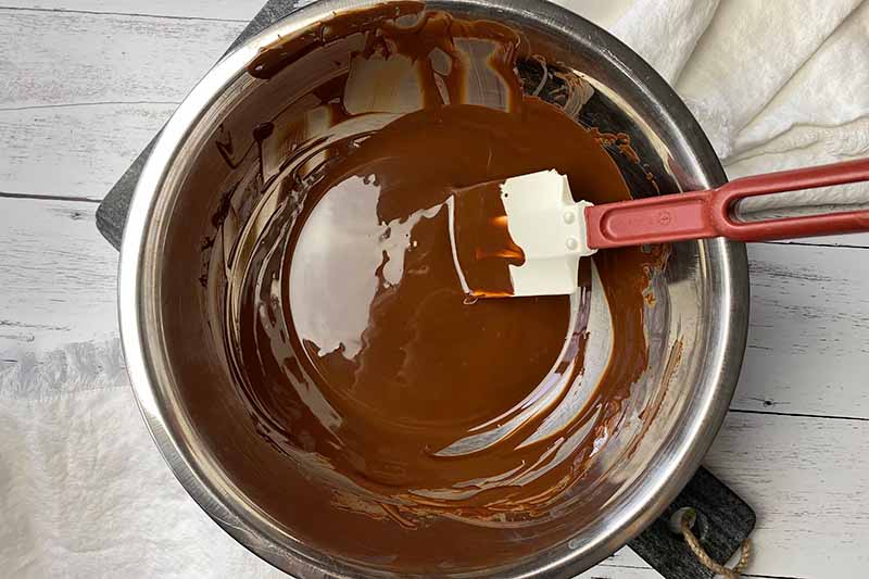 Horizontal image of melted chocolate in a bowl with a spatula.