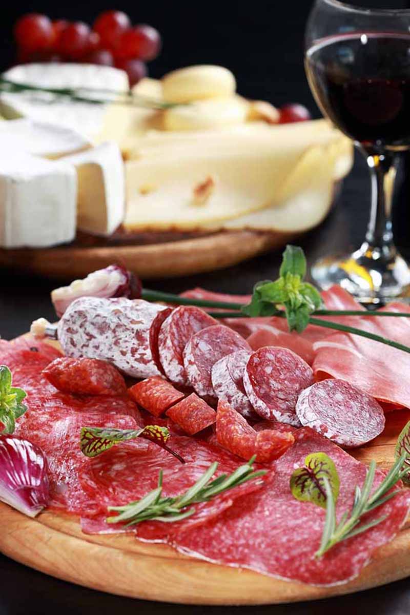 Vertical image of assorted charcuterie on an appetizer spread.