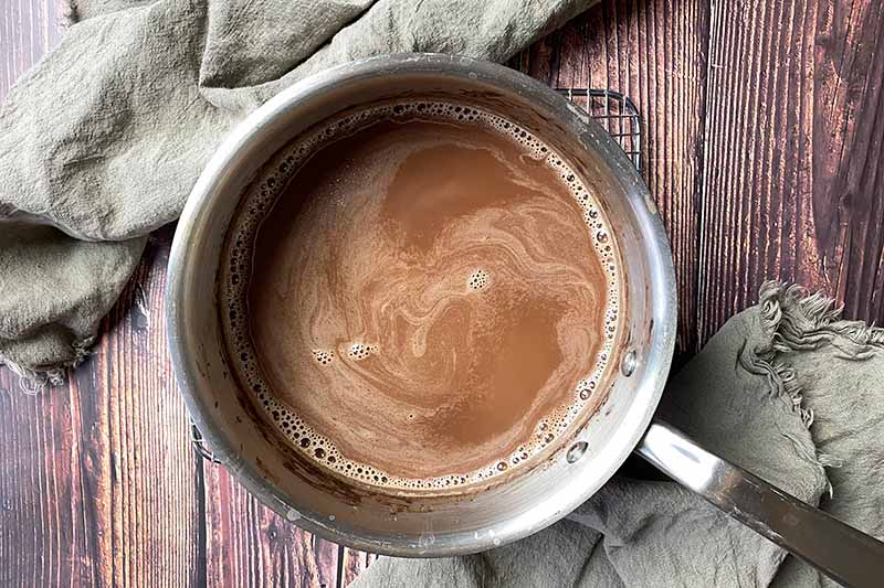 Horizontal image of a chocolate and milk mixture in a pot.