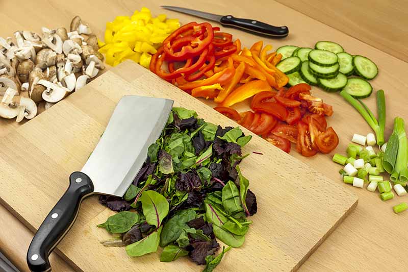 Horizontal image of a knife next to a board with prepared assorted fresh food.