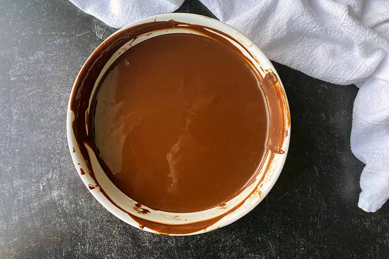 Horizontal image of a creamy melted brown mixture in a white bowl.