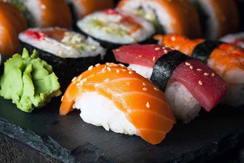 Horizontal image of a sushi spread on a slate.