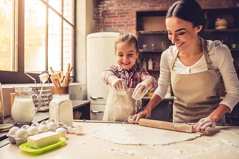 Horizontal image of a mom and daughter baking together.