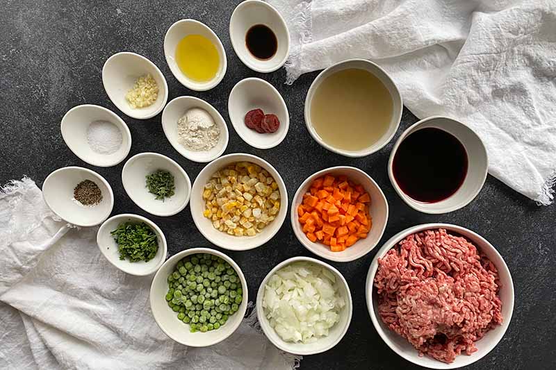 Horizontal image of measured and prepped ingredients in assorted white bowls.