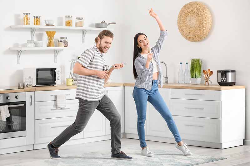 Horizontal image of a man and woman having fun and dancing together in a kitchen.