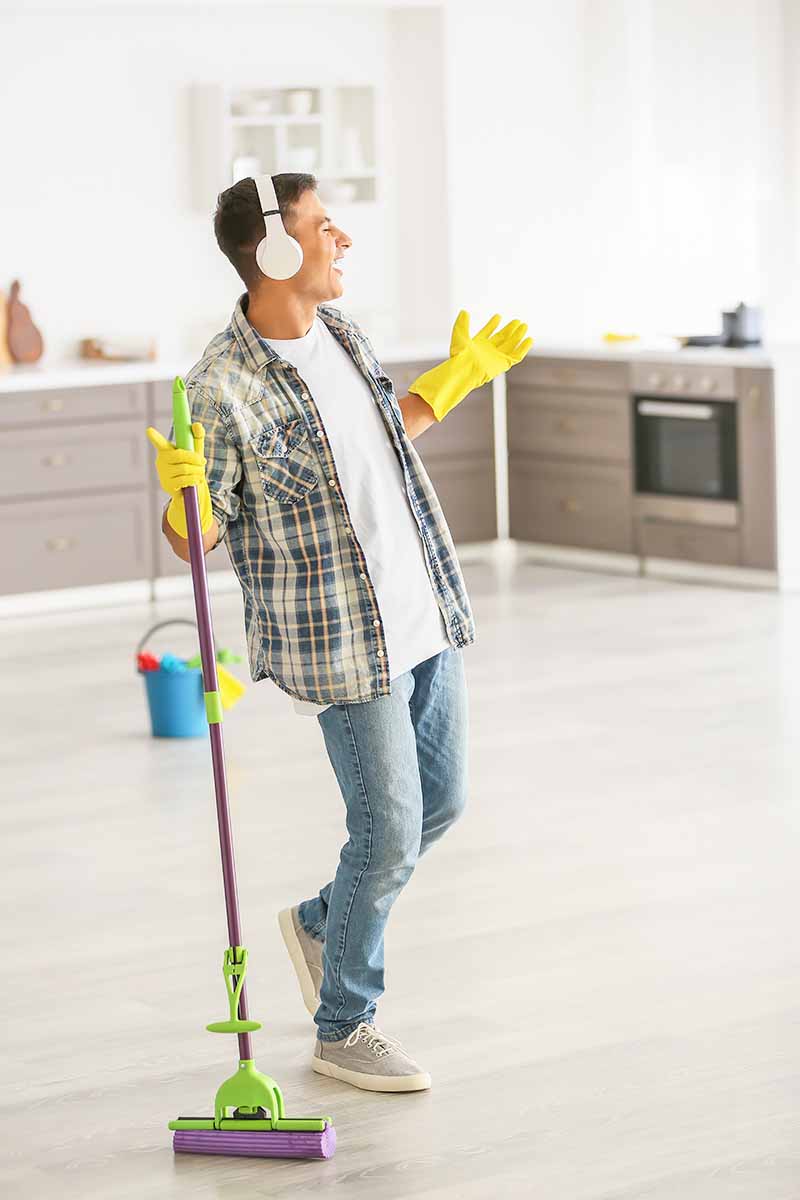 Vertical image of a man listening to music while cleaning.