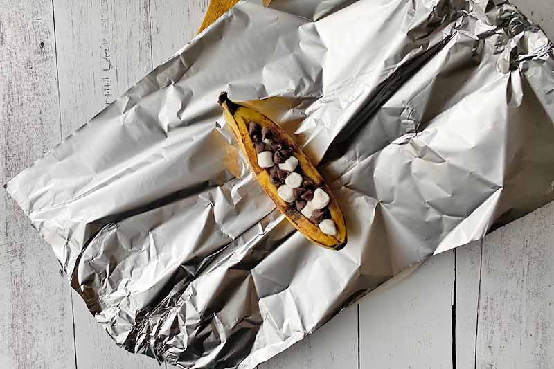 Horizontal image of wrapping a stuffed fruit in aluminum foil.