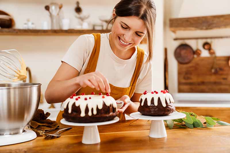 Horizontal image of a woman decorating cakes.