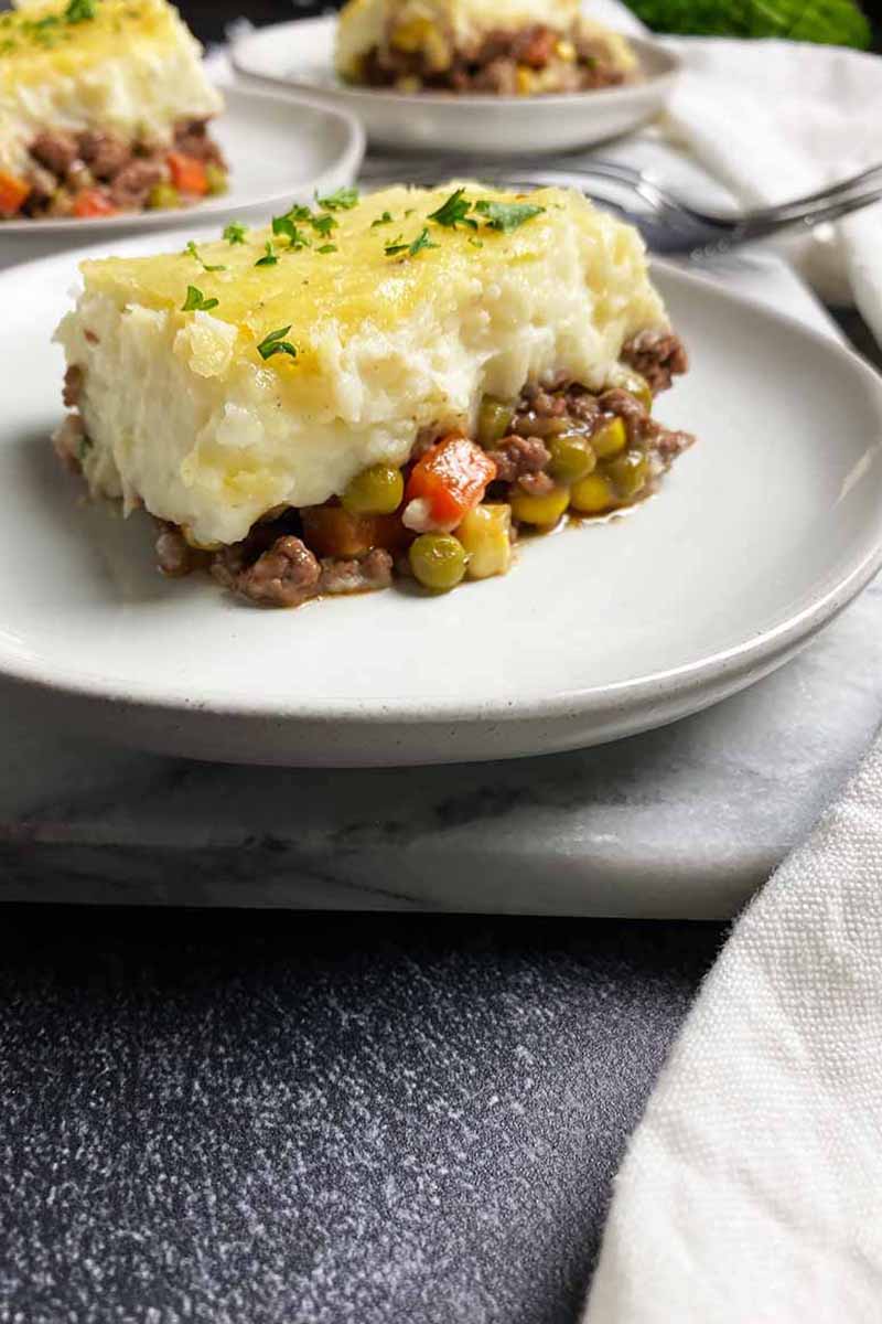 Vertical image of a large serving of a shepherd's pie layered recipe on a white plate.