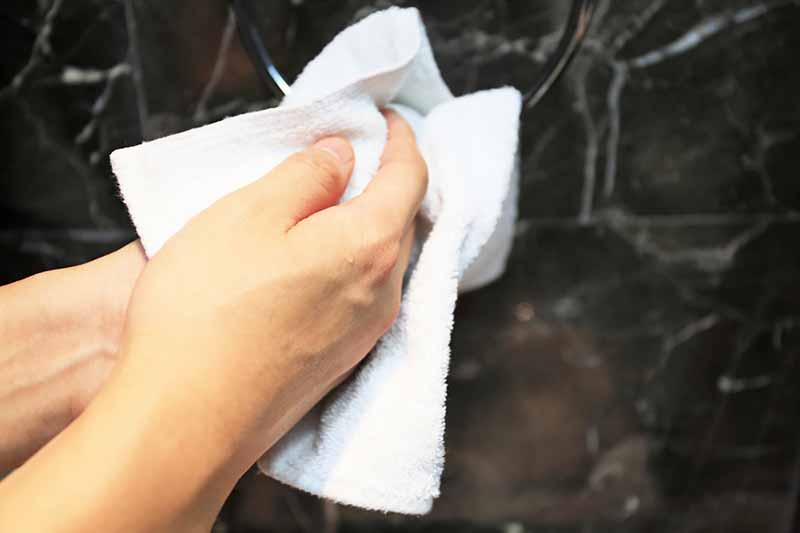 Horizontal image of drying off clean hands with a white towel.
