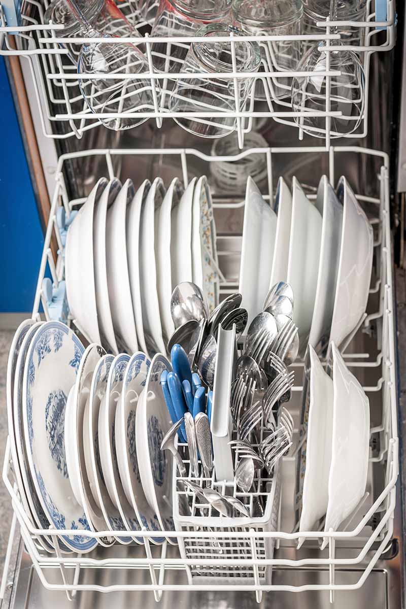 Vertical image of loaded plates and silverware in a dishwasher.