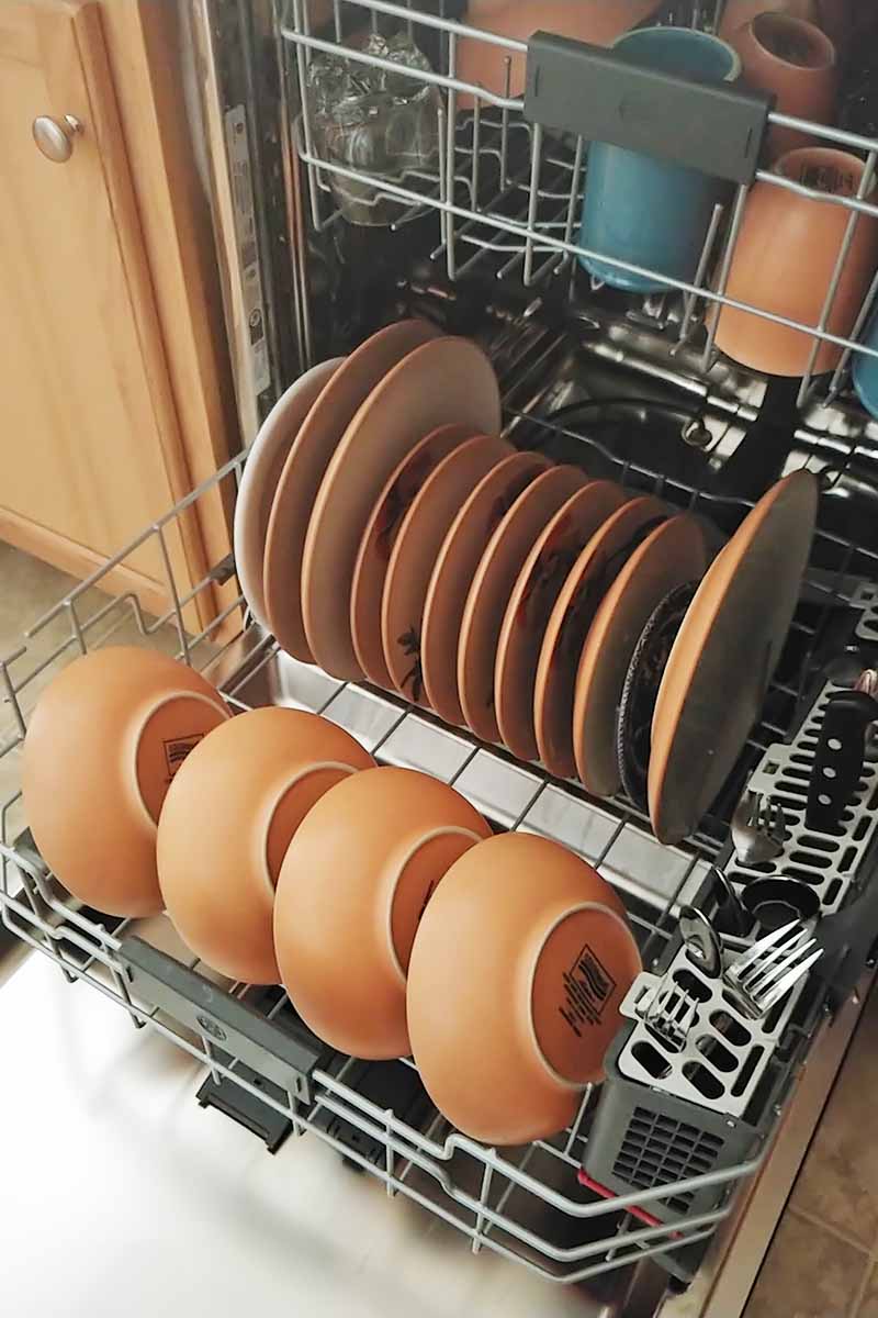 Vertical image of well-organized bowls and plates in a dishwasher.