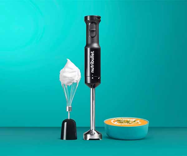 Image of a handheld appliance next to a whisk attachment and a bowl of soup with a teal background.
