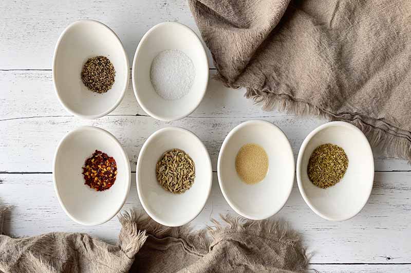 Horizontal image of measured spices in oblong white bowls.