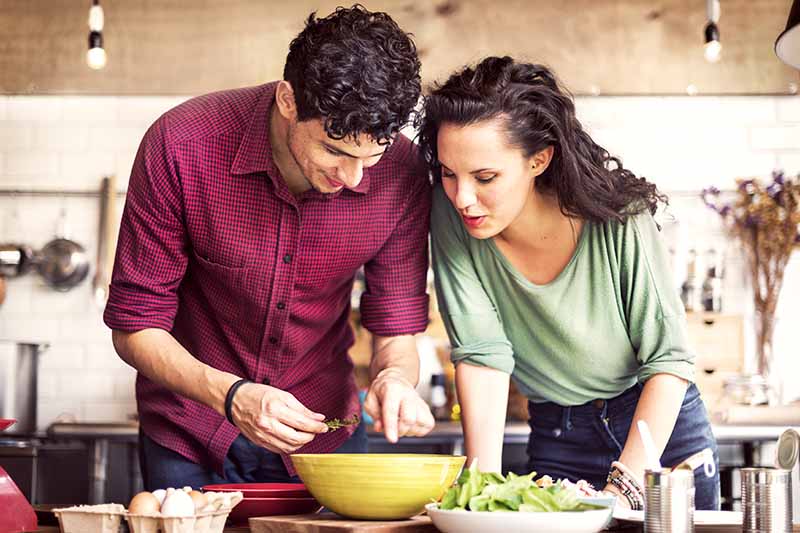 Horizontal image of a woman and man preparing a salad.