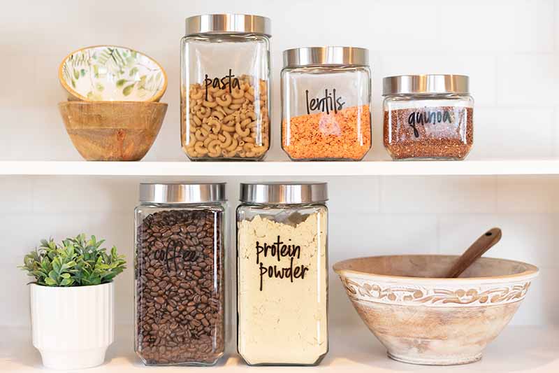 Horizontal image of labeled jars full of dry food on shelves.