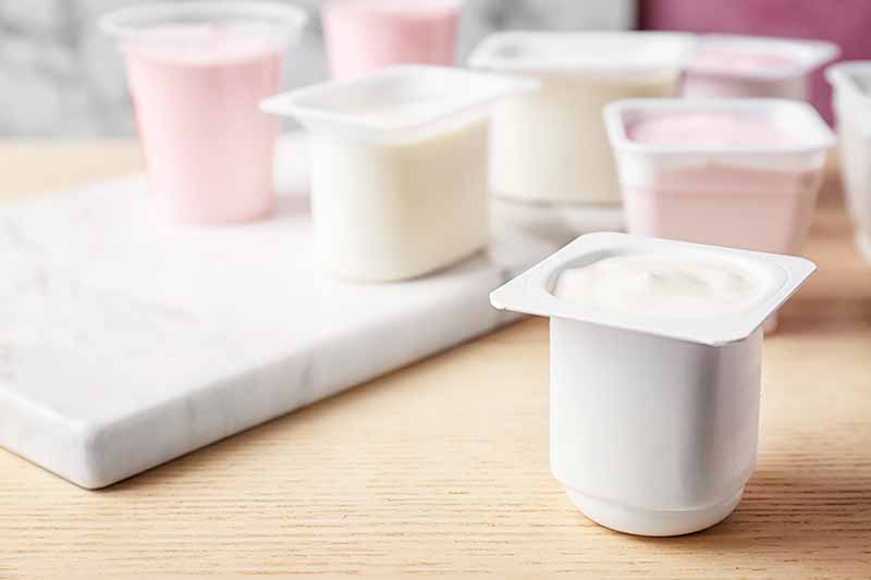 Horizontal image of plastic cups filled with a creamy white and light pink food.