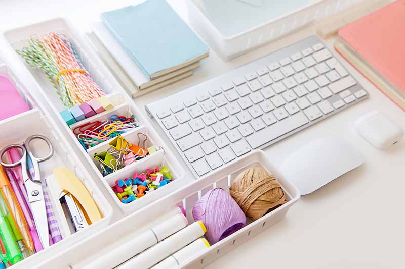 Horizontal image of neatly arranged office supplies in containers.