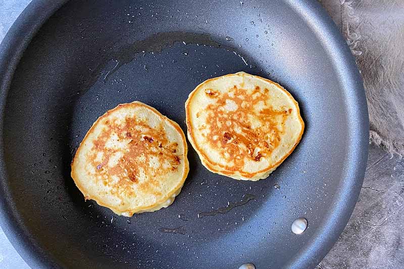 Horizontal image of cooking flapjacks in a greased skillet.