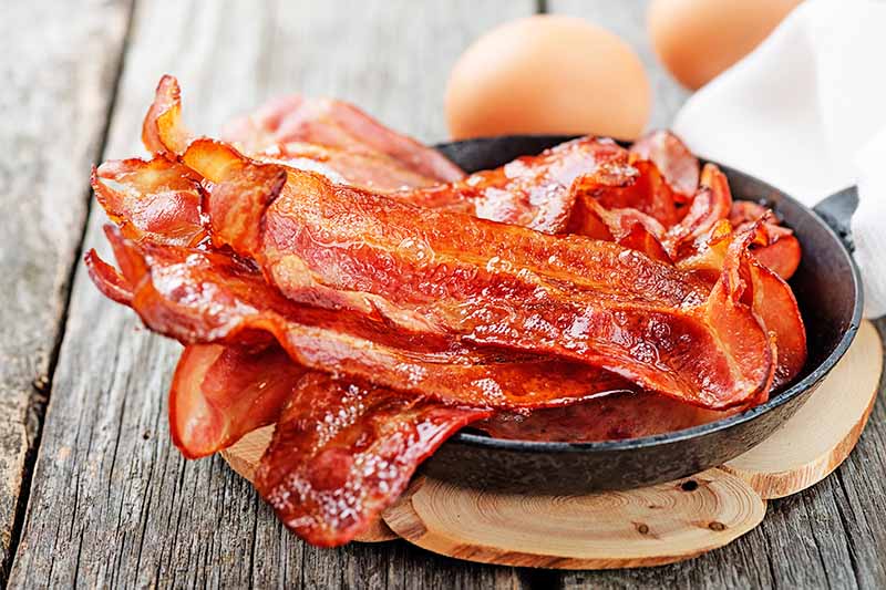 Horizontal image of cooked crispy bacon in a small skillet.