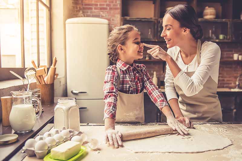 Vertical image of a mother and daughter having fun in the kitchen.