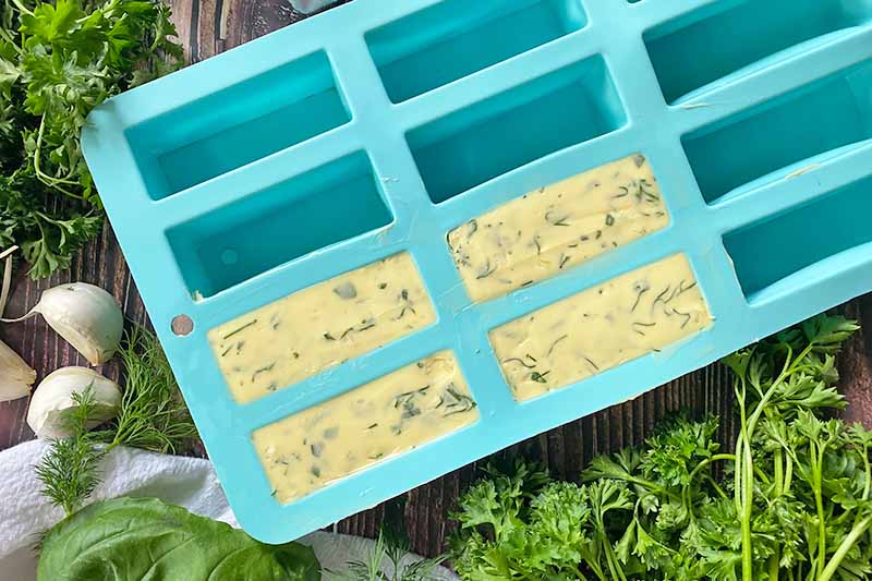 Horizontal image of mini rectangular molds that are partially filled with a light yellow mixture.