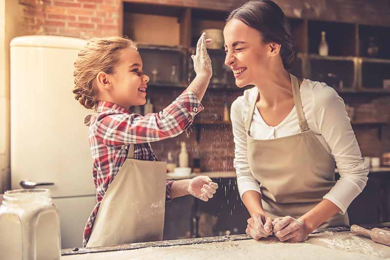 Vertical image of a mother and daughter having fun in the kitchen.