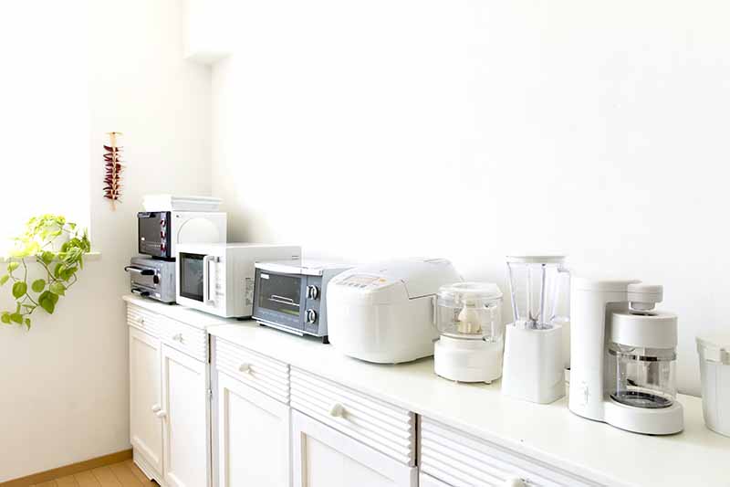 Horizontal image of assorted appliances on top of a kitchen countertop.