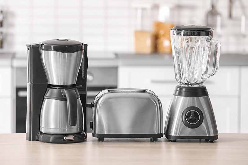 Horizontal image of a row of appliances on a countertop.