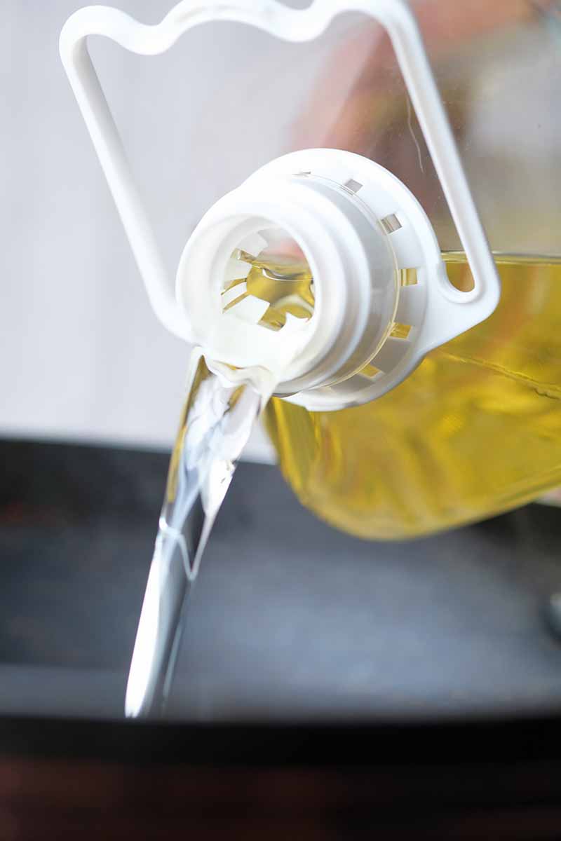 Vertical image of pouring vegetable oil into a pan.