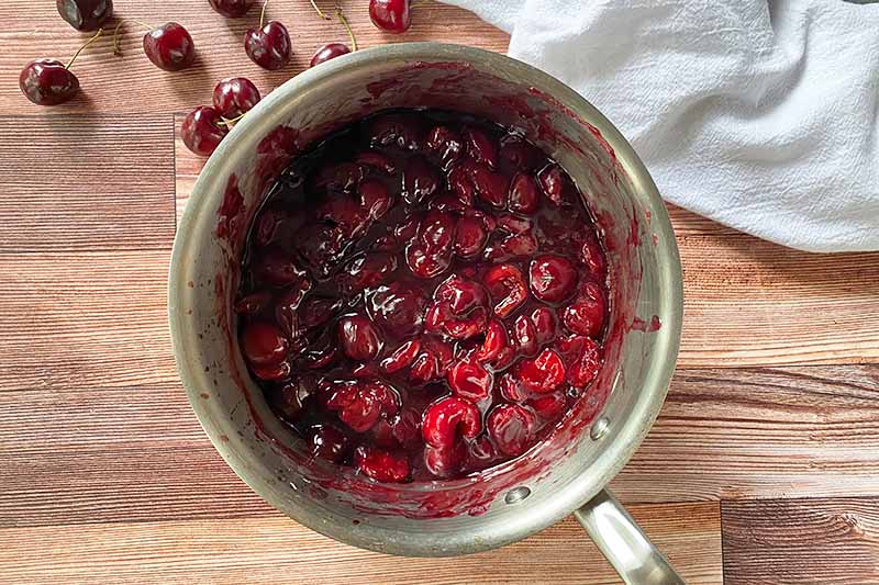 Horizontal image of cooked cherries in a pot.