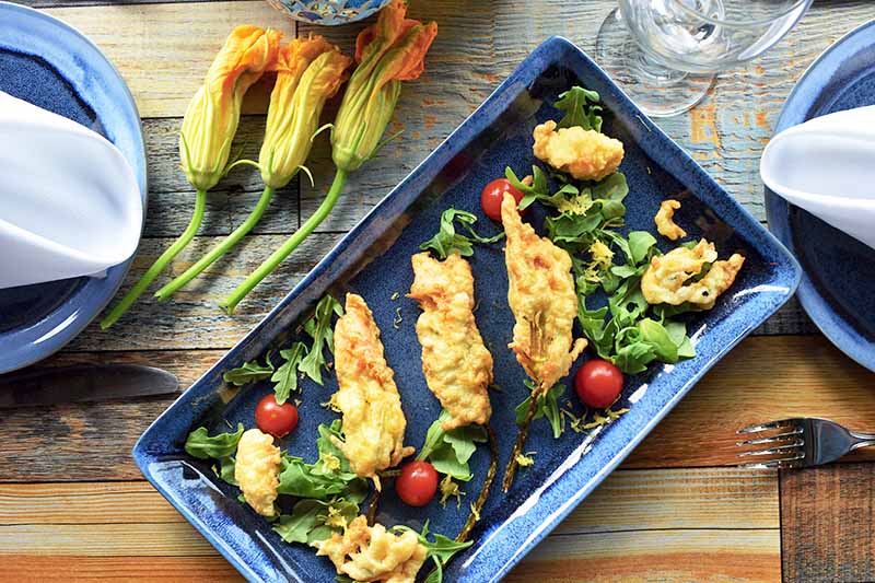 Horizontal image of stuffed and fried zucchini blossoms on a tray