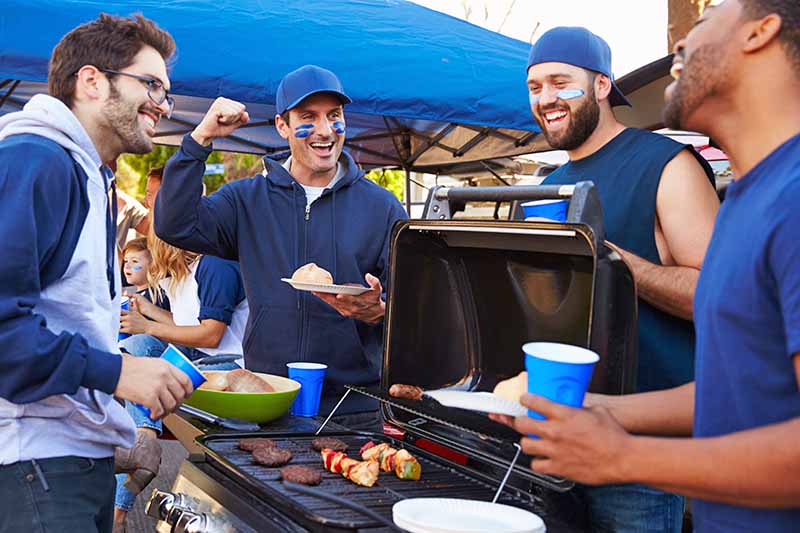 Horizontal image of men tailgating during a sports event.
