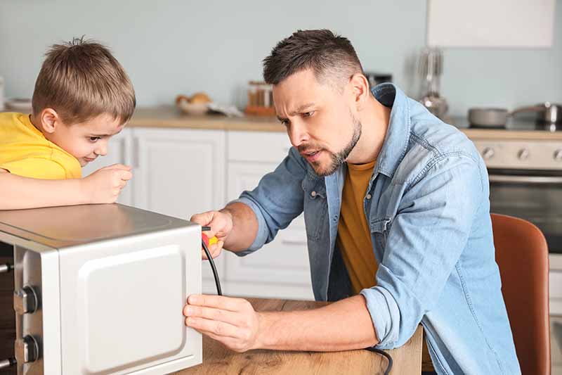 Horizontal image of a man and child fixing an electric appliance.